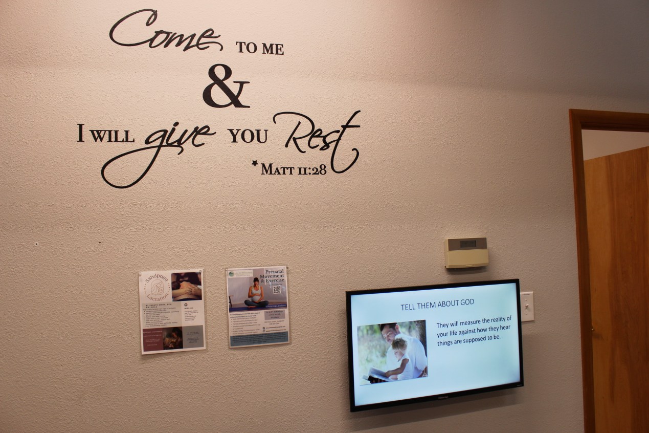 The words, "Come to me & I will give you rest" are displayed on a wall. A TV monitor mounted on the wall shows a slide that reads, "Tell them about God. They will measure the reality of your life against how they hear things are supposed to be."