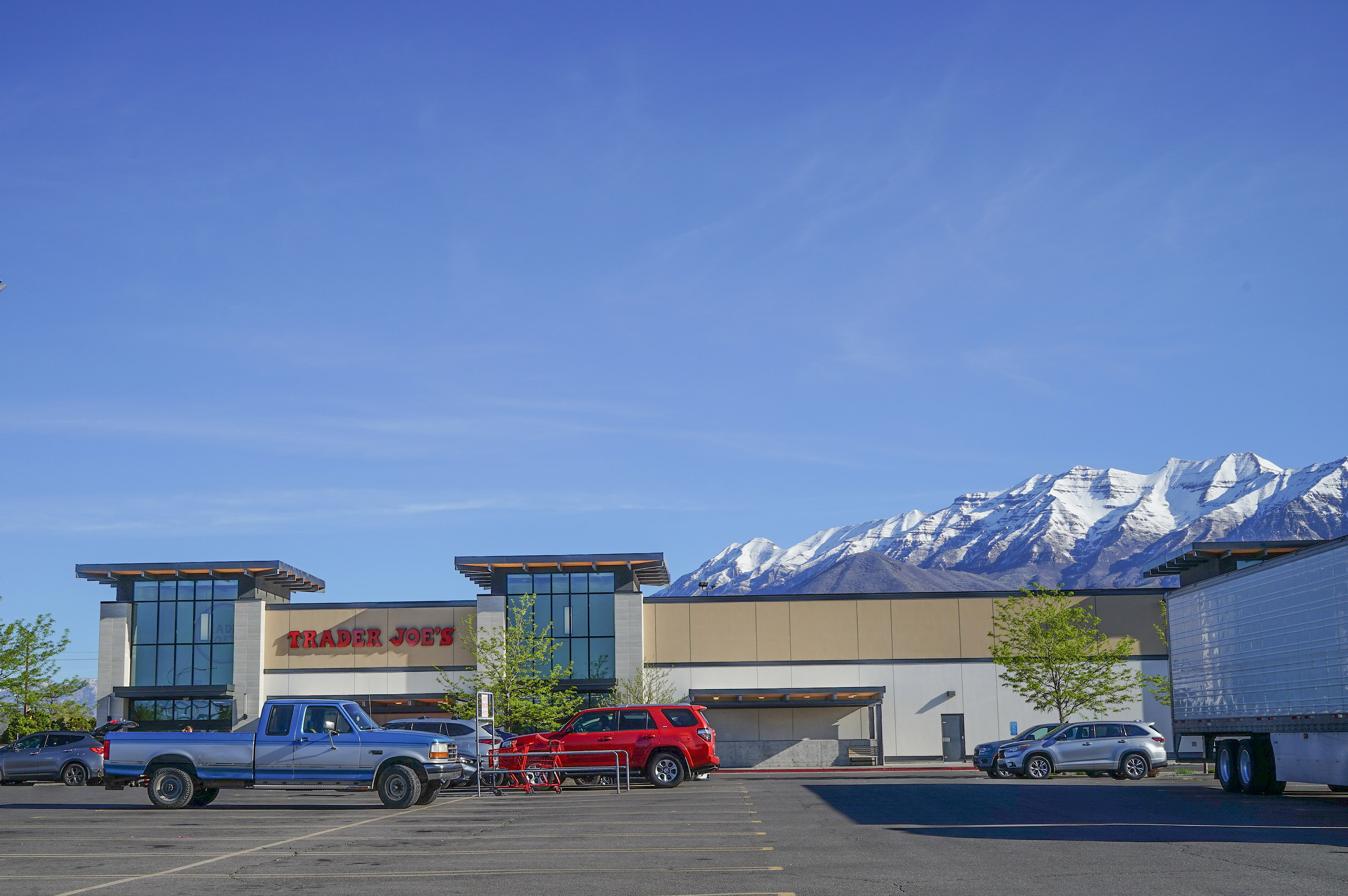 A photo of a Trader Joe's parking lot. Mountains are seen peaking out from behind the building.