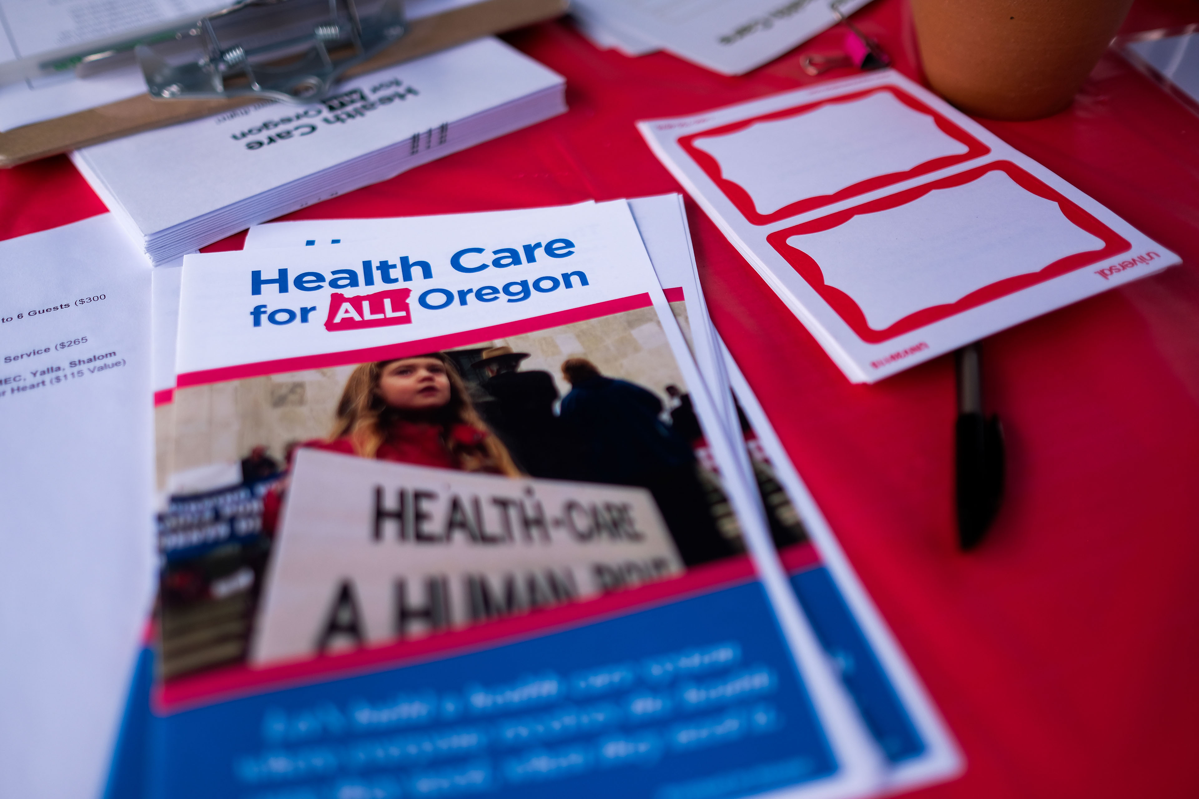 Pamphlets with information about "Health Care for All Oregon" are stacked on a red table.