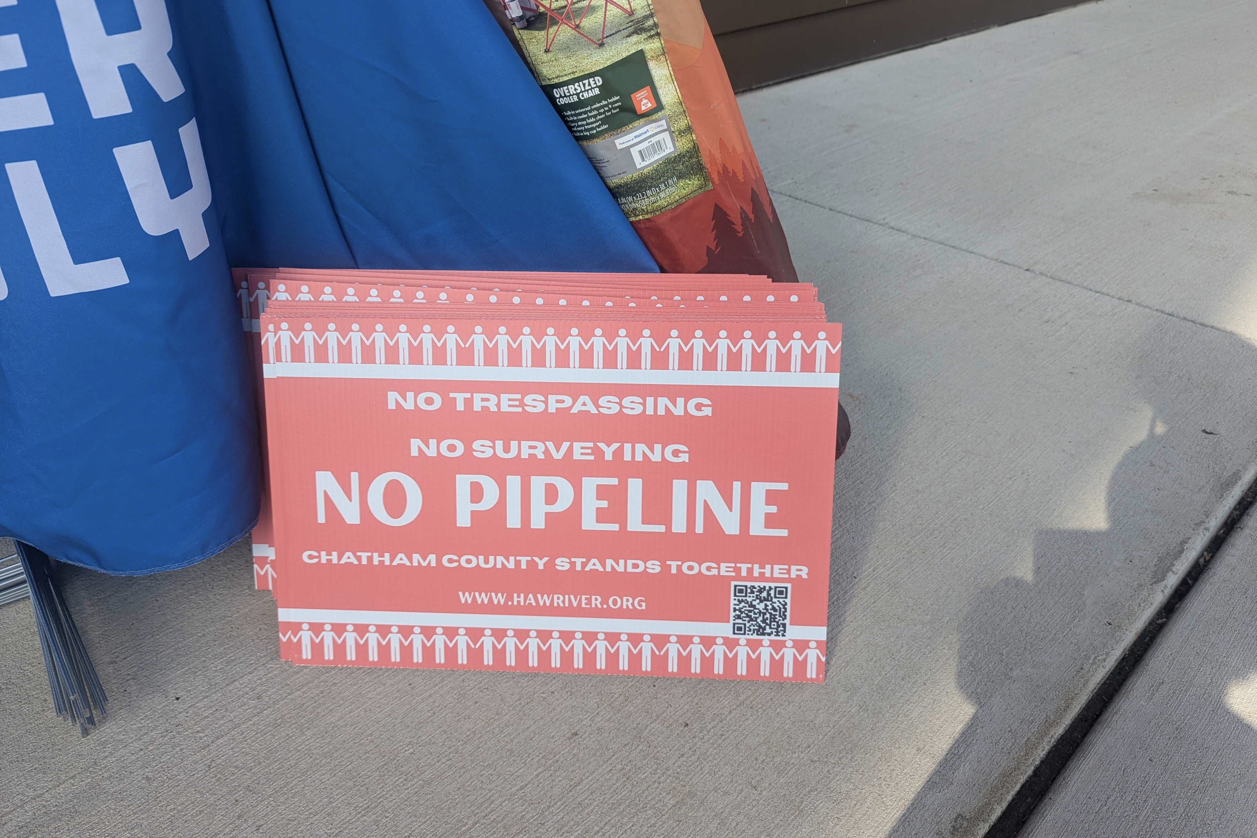 A close-up photo of a stack of red signs that read, "No trespassing. No surveying. No pipeline. Chatham County stands together."